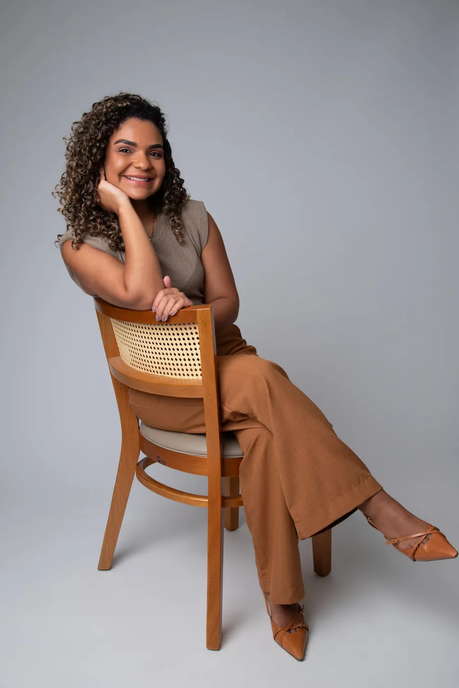 Jéssica Wesley sentada em cadeira de madeira, sorrindo